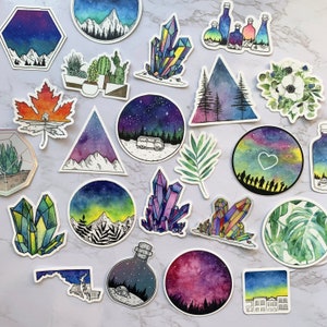 May include: A collection of 18 watercolor stickers featuring various designs, including crystals, mountains, stars, and plants. The stickers are all on a white background.