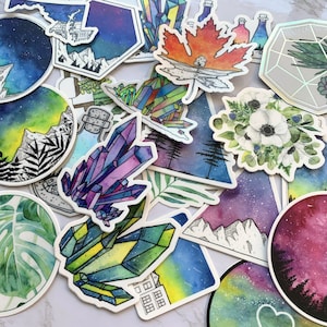 May include: A collection of colorful, hand-painted stickers featuring various designs, including crystals, flowers, mountains, and celestial scenes. The stickers are perfect for adding a touch of whimsy and personalization to laptops, water bottles, journals, and more.