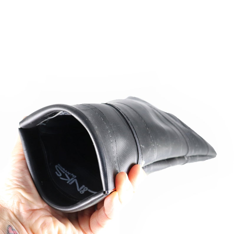 May include: A black recycled inner tube pouch with the word "BINKs" printed on the inside. The pouch is open and turned inside out, showing the seam.