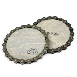 May include: Two round wooden coasters with a bicycle design. The coasters are made from recycled bicycle chains.