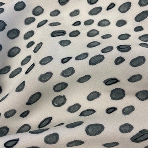 May include: White fabric with a black polka dot pattern. The fabric is textured and has a subtle sheen.