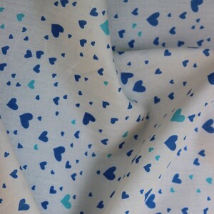 May include: White fabric with a blue and light blue heart pattern. The fabric is folded in half and the pattern is visible on both sides.