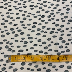 May include: White fabric with a repeating pattern of small, dark grey oval shapes. A yellow measuring tape with black markings is placed across the fabric. The tape reads "1 2 3 4 120in 5 MADE IN 6 CHINA 7".