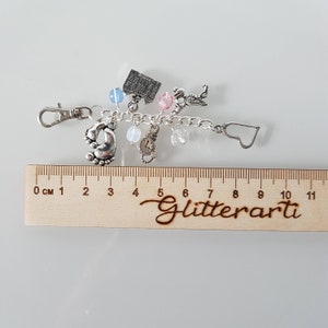 May include: Silver charm bracelet featuring a selection of charms, including a house, a clock, a heart, and a pair of baby footprints. The bracelet measures approximately 10 cm in length and has a silver clasp.