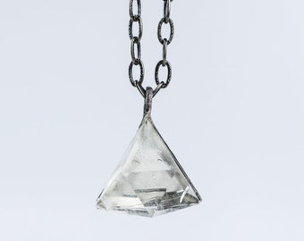 May include: A silver chain necklace with a clear crystal pendant shaped like a diamond.
