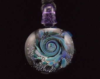 May include: A glass pendant necklace with a swirling blue, green, and white design. The pendant is round and has a black cord.