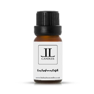 May include: A small brown glass bottle with a black cap. The bottle has a white label with the text "JL CANDLES" and "Car Freshener Refill". The website address "www.lindsaylucascandles.co.uk" is also printed on the label. The bottle is designed for car freshener refills.