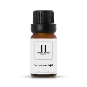 May include: A small brown glass bottle with a black lid. The bottle is labelled with the text "JL Candles" and "Car Freshener Refill". The website address "www.lindsaylucascandles.co.uk" is printed on the label.