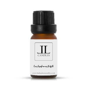 May include: A small brown glass bottle with a black cap. The bottle has a white label with the text "JL Candles" and "Car Freshener Refill" and the website address "www.lindsaylucascandles.co.uk".