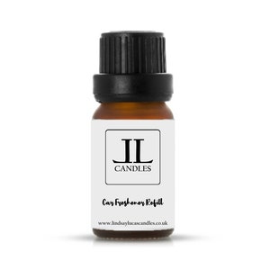 May include: A small brown glass bottle with a black lid. The bottle is labelled with the text "JL Candles" and "Car Freshener Refill". The website address "www.lindsaylucascandles.co.uk" is printed on the label.