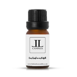 May include: A small brown glass bottle with a black cap. The bottle has a white label with the text "JL Candles" and "Car Freshener Refill" and the website address "www.lindsaylucascandles.co.uk".