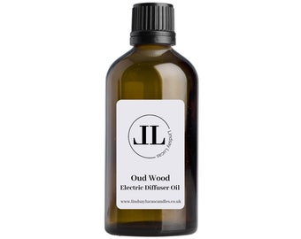 Op de afbeelding: Een bruine glazen fles met een zwarte dop en een wit etiket. Het etiket heeft een zwarte cirkel met de letters "JL" erin. De tekst op het etiket luidt "Oud Wood Electric Diffuser Oil" en "www.lindsaylucascandles.co.uk".
