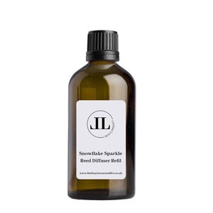 May include: A brown glass bottle with a black cap and a white label. The label features the initials "JL" inside a circle, and the text "Snowflake Sparkle Reed Diffuser Refill". The website address is also visible.