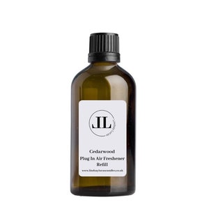 May include: A brown glass bottle with a black cap and a white label. The label has the text "Cedarwood Plug In Air Freshener Refill" and a website address. The bottle is a refill for a plug-in air freshener.