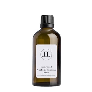 May include: A brown glass bottle with a black cap and a white label. The label has a black circle with the letters "JL" inside. The text on the label reads "Cedarwood Plug In Air Freshener Refill www.lindseylucascandles.co.uk".
