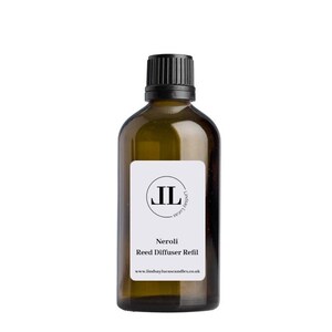 Op de afbeelding: Een bruine glazen fles met een zwarte dop en een wit etiket. Het etiket heeft een zwarte cirkel met de letters "JL" erin. De tekst op het etiket luidt "Neroli Reed Diffuser Refill" en "www.lindsaylucascandles.co.uk".