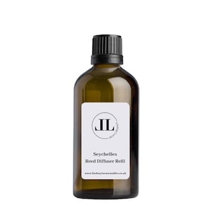 May include: A brown glass bottle with a black cap and a white label. The label has a black circle with the letters "JL" inside. The text on the label reads "Seychelles Reed Diffuser Refill" and "www.lindsaylucascandles.co.uk".