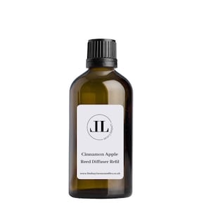 May include: A brown glass bottle with a black lid and a white label. The label has a black circle with the letters "JL" inside. The text on the label reads "Cinnamon Apple Reed Diffuser Refill" and "www.lindsaylucascandles.co.uk".