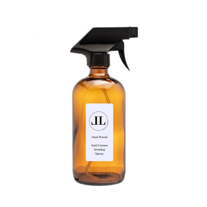 May include: An amber glass spray bottle with a black trigger. The bottle features a white label with the text "JL", "Oud Wood", and "Anti Crease Ironing Spray". The product is designed for ironing and crease removal.