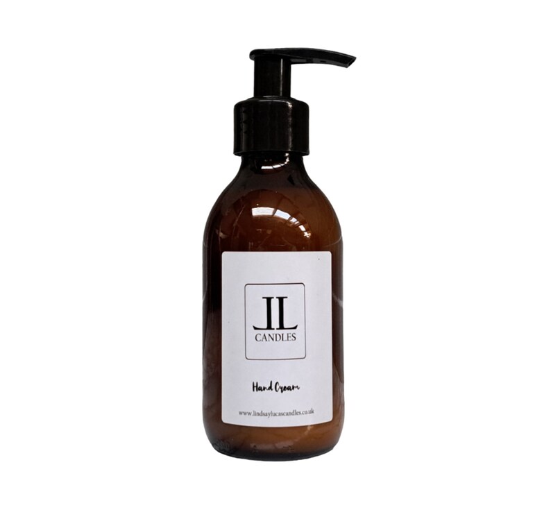 May include: A brown glass bottle with a black pump dispenser. The bottle has a white label with the text "IL CANDLES" and "Hand Cream". The website address www.lindsaylucascandles.co.uk is printed at the bottom of the label.
