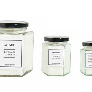 Puede incluir: Tres frascos de vidrio de sales de ba&ntilde;o con tapas negras. Los frascos son hexagonales y contienen sales de ba&ntilde;o blancas. Las etiquetas de los frascos dicen "Lavender Bath Salts Sels de Bain Lindsay Lucas".