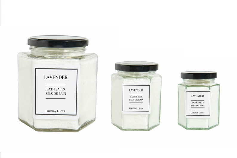 Puede incluir: Tres frascos de vidrio de sales de ba&ntilde;o con tapas negras. Los frascos son hexagonales y contienen sales de ba&ntilde;o blancas. Las etiquetas de los frascos dicen "Lavender Bath Salts Sels de Bain Lindsay Lucas".