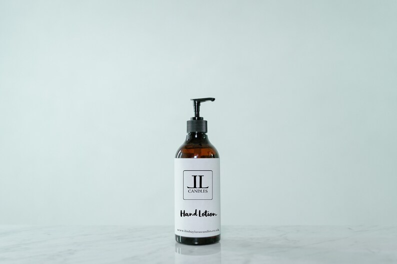 May include: A brown glass bottle with a black pump dispenser filled with hand lotion. The bottle has a white label with the text "JL Candles" and "Hand Lotion".