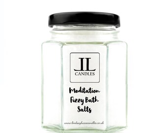 May include: A glass jar with a black lid filled with white bath salts. The jar has a label that says "IL Candles" and "Meditation Fizzy Bath Salts". The website address "www.lindsayslucascandles.co.uk" is printed on the label.