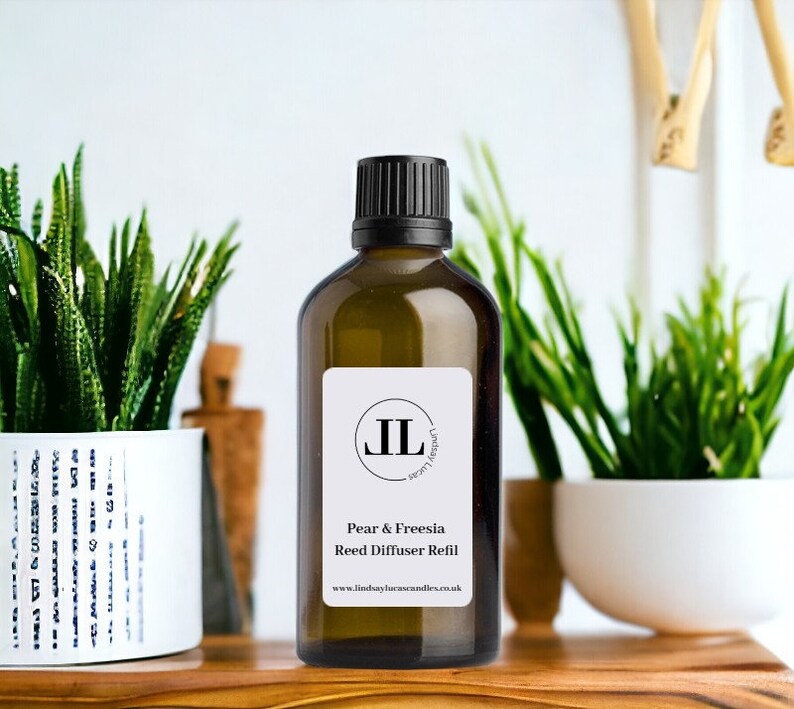 Puede incluir: Una botella de vidrio marr&oacute;n con una tapa negra y una etiqueta blanca. La etiqueta tiene un logotipo negro con las letras "JL" y el texto "Pear & Freesia Reed Diffuser Refill" y "www.lindsaylaurencandles.co.uk".