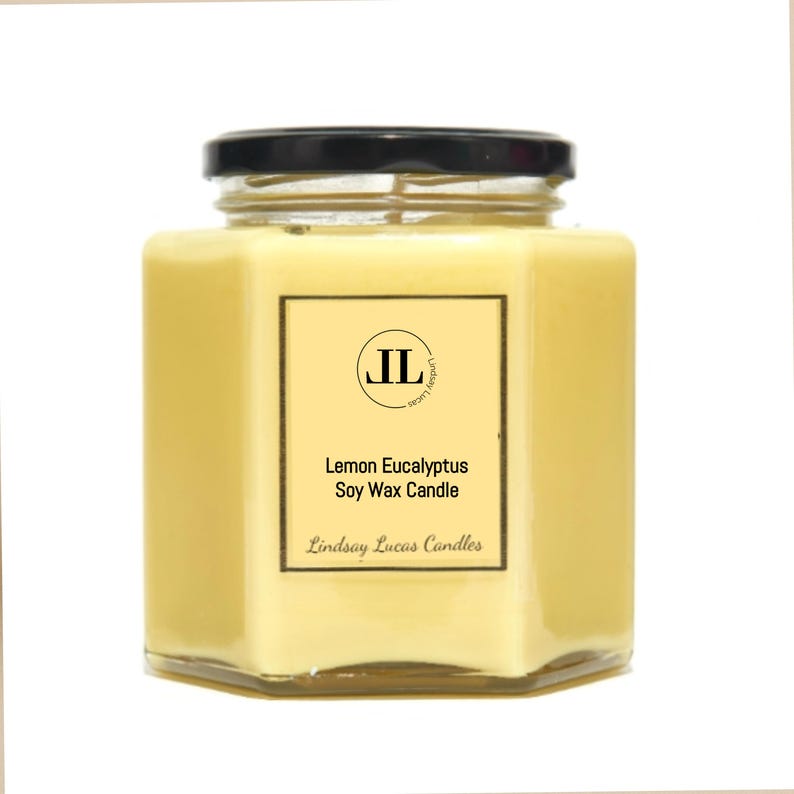 May include: A hexagonal glass jar candle with a black lid. The candle is filled with yellow wax and has a label that reads "Lemon Eucalyptus Soy Wax Candle" with the brand name "Lindsay Lucas Candles".