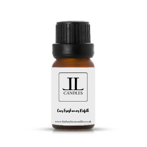 May include: A small brown glass bottle with a black cap. The bottle is labelled with the text "JL Candles" and "Car Freshener Refill". The website address "www.lindsaylucascandles.co.uk" is printed on the label.