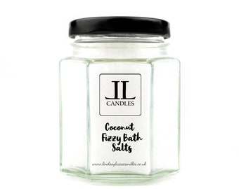 May include: A glass jar with a black lid filled with white bath salts. The jar has a label that says "Coconut Fizzy Bath Salts" and "JL Candles" with the website address "www.lindsayjacascandles.co.uk".