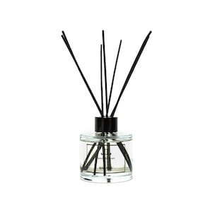 May include: A clear glass bottle with a black lid and black diffuser sticks. The bottle contains a clear liquid and has a label that reads "Reed Diffuser" and "Banana".