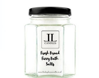 May include: A clear glass jar with a black lid filled with white bath salts. The jar has a label that says "IL Candles" and "Fresh Bread Fizzy Bath Salts" with the website address "www.lindsayslucascandles.co.uk".