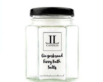 May include: A clear glass jar with a black lid filled with white bath salts. The jar has a label that says "Gingerbread Fizzy Bath Salts" and "IL Candles" with the website address "www.lindsayslucascandles.co.uk".