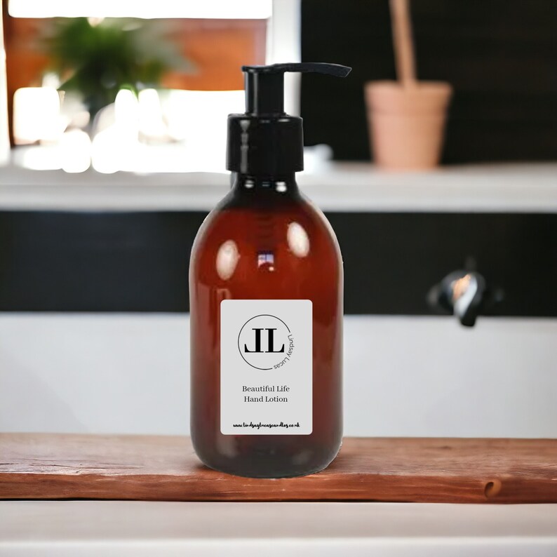 May include: A brown glass bottle with a black pump dispenser filled with hand lotion. The bottle has a white label with the text "JL London Luxe" and "Beautiful Life Hand Lotion" and a website address.