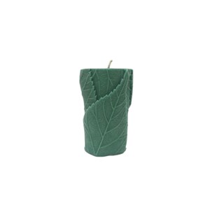 May include: A green pillar candle with a leaf design. The candle is made of soy wax and has a natural scent.