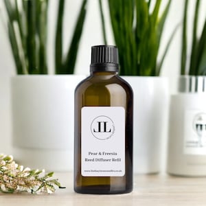 Puede incluir: Una botella de vidrio marr&oacute;n con una tapa negra y una etiqueta blanca. La etiqueta tiene un logotipo negro y el texto "Pear & Freesia Reed Diffuser Refill" y "www.lindsaylucascandles.co.uk".