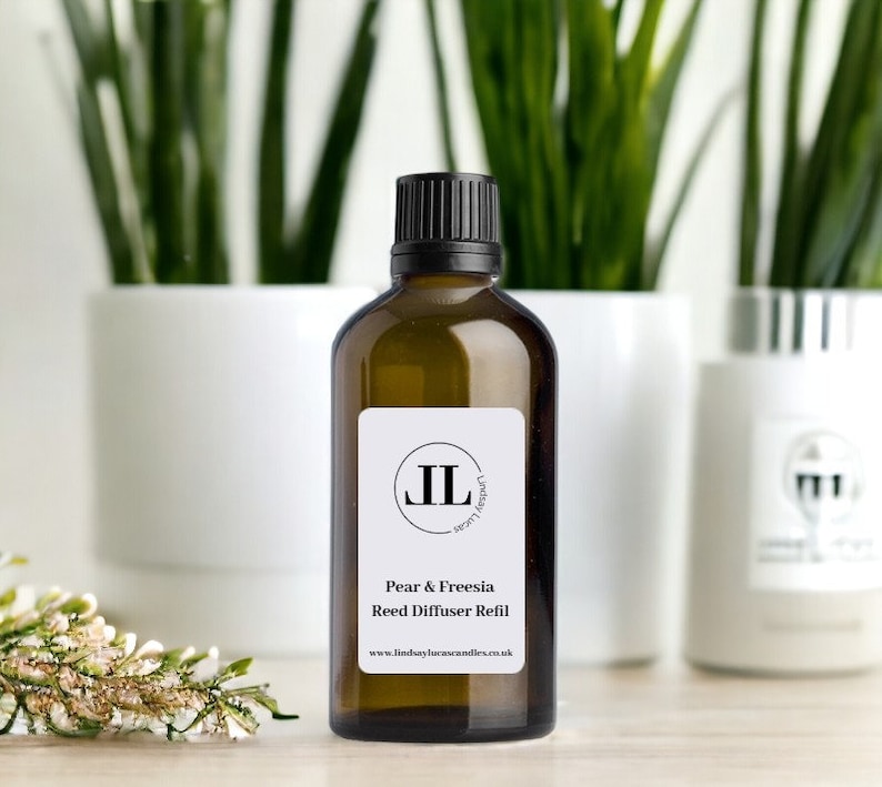 Puede incluir: Una botella de vidrio marr&oacute;n con una tapa negra y una etiqueta blanca. La etiqueta tiene un logotipo negro y el texto "Pear & Freesia Reed Diffuser Refill" y "www.lindsaylucascandles.co.uk".