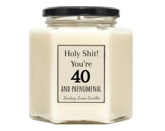 May include: A white candle in a glass jar with a black lid. The label on the jar reads "Holy Shit! You're 40 AND PHENOMENAL" with the text "Lindsay Lucas Candles" below.