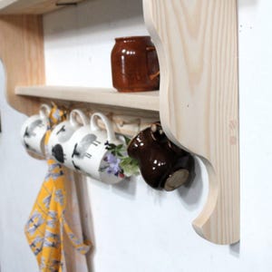 Detail of a wooden wall shelf in natural pine showing a curvy profile.