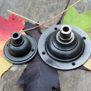 May include: Two black metal ceiling light fixtures with a round, dome-shaped design. The larger fixture has a diameter of approximately 15 cm and the smaller fixture has a diameter of approximately 7.5 cm.