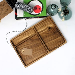 May include: A wooden serving tray with three compartments. The tray is made of dark wood and has a natural finish. The tray is ideal for serving snacks, appetisers, or desserts.