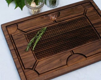 May include: A large, rectangular, dark brown wooden cutting board with a raised, textured grid pattern in the center. The board has decorative carvings around the edges and a small amount of pink Himalayan salt on the surface.
