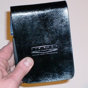 May include: A black leather notebook cover with the embossed text "The Coven" in silver lettering.