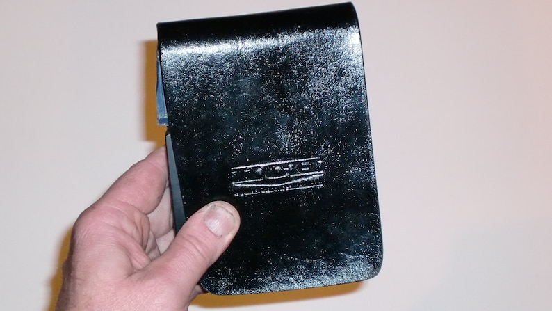 May include: A black leather notebook cover with the embossed text "The Coven" in silver lettering.