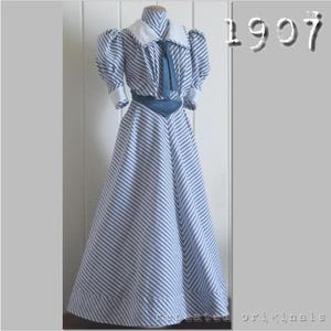 May include: A white and blue striped dress with a blue sash and a white collar. The dress has a puffed sleeve and a long skirt. The dress is labeled "1907".