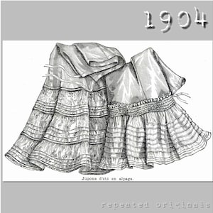 May include: A black and white illustration of two skirts from 1904. The skirts are made of a lightweight fabric and have multiple layers of ruffles. The text "Jupons d'été en alpaga." is printed below the skirts.