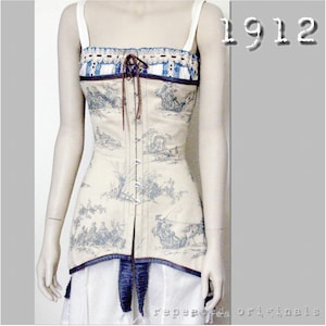 May include: Cream corset top with a blue and white toile design. It has a square neckline, thin white straps, and a lace-trimmed edge. The corset is laced up the front with brown cord and has a blue trim at the bottom. The number "1912" is in the upper right corner.