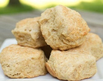 May include: A stack of five golden brown biscuits on a white plate. The biscuits are soft and fluffy, and they look delicious.